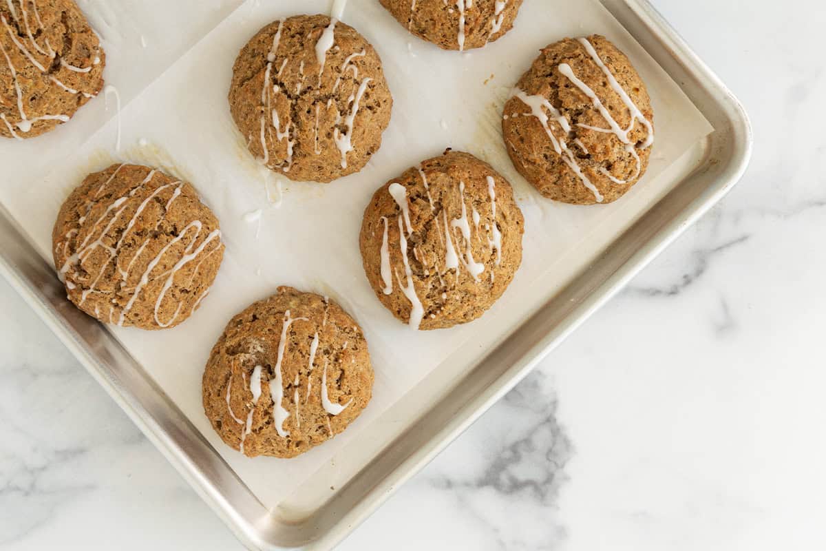 Banana scones on baking sheet with frosting drizzle.