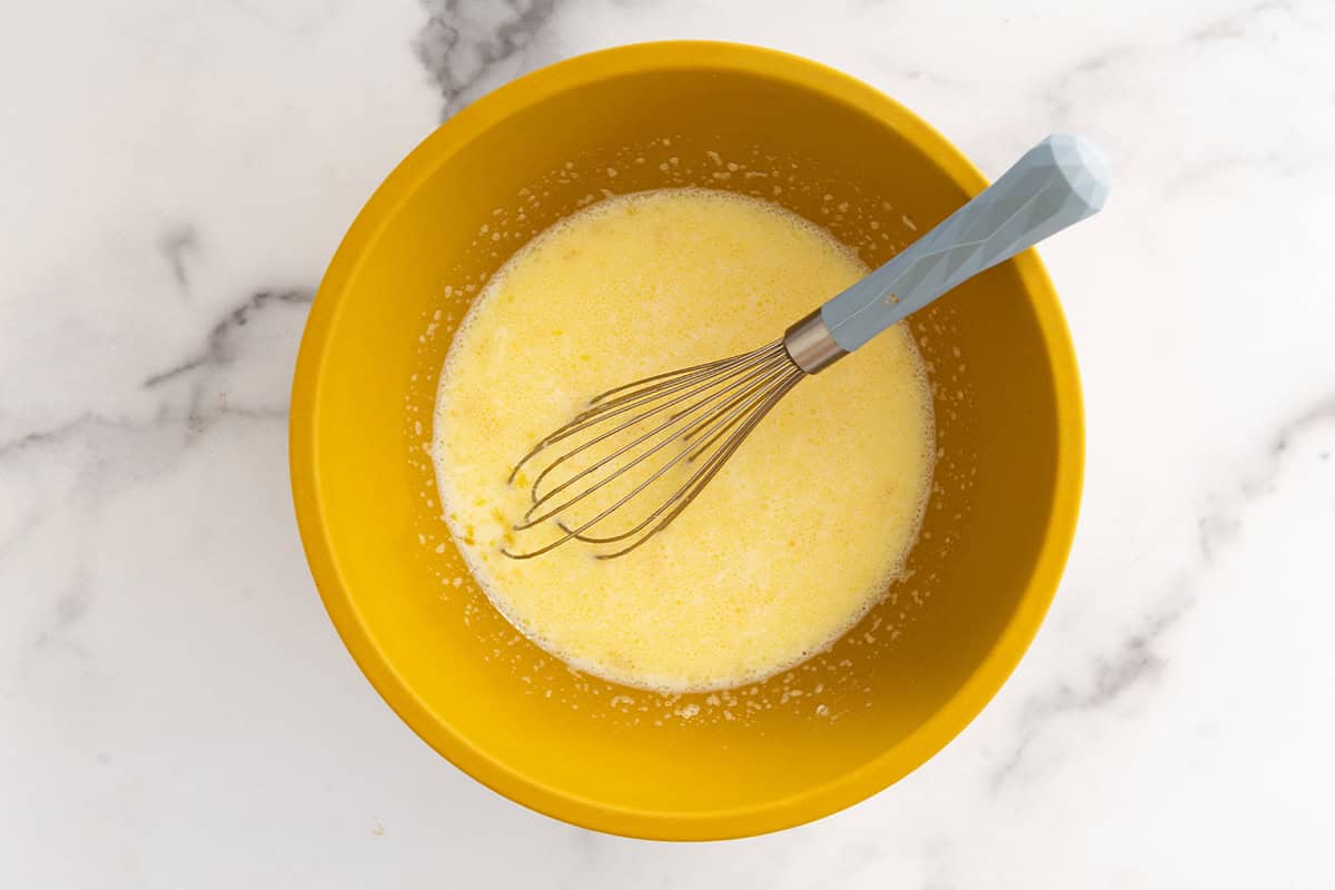 Wet ingredients for vegetable pancakes in yellow bowl.