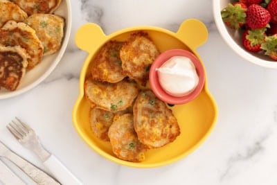 Vegetable pancakes on yellow plate with dip.