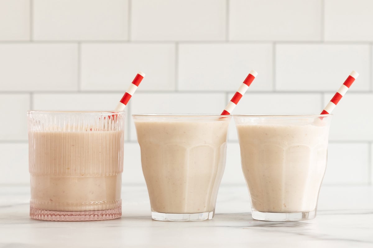 Apple smoothie in three glasses with straws.