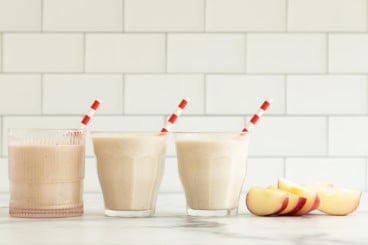 Apple smoothie in three glasses with straws.