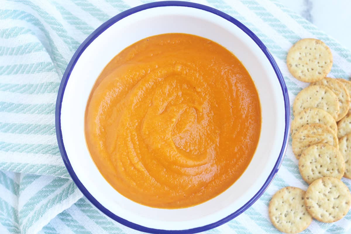 vegan tomato soup in white bowl with crackers.