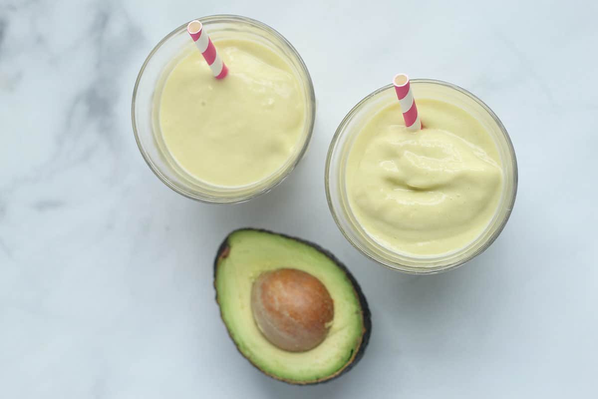 avocado mango smoothies in cups on counter.