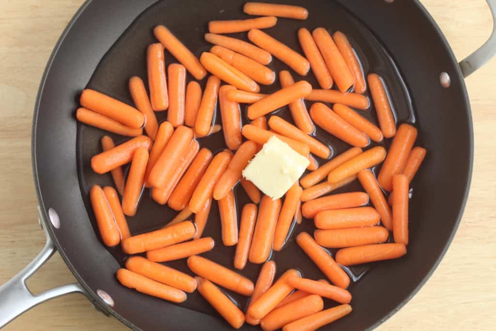 Baby carrots and butter in frying pan.