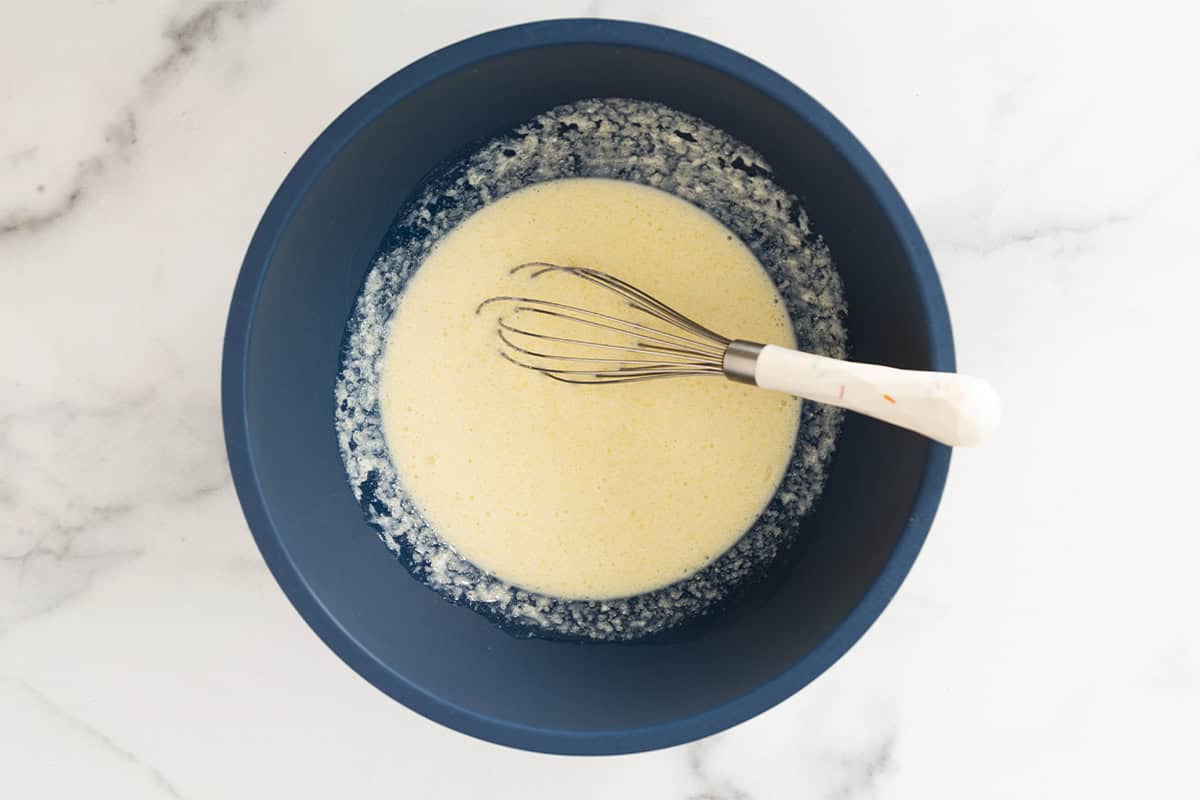 Wet ingredients for chocolate baked donuts in blue bowl with whisk.