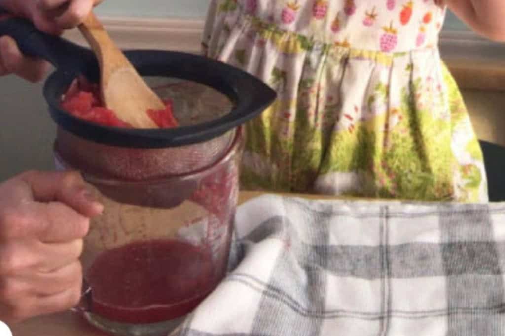 Straining watermelon juice into pitcher with mom and daughter.