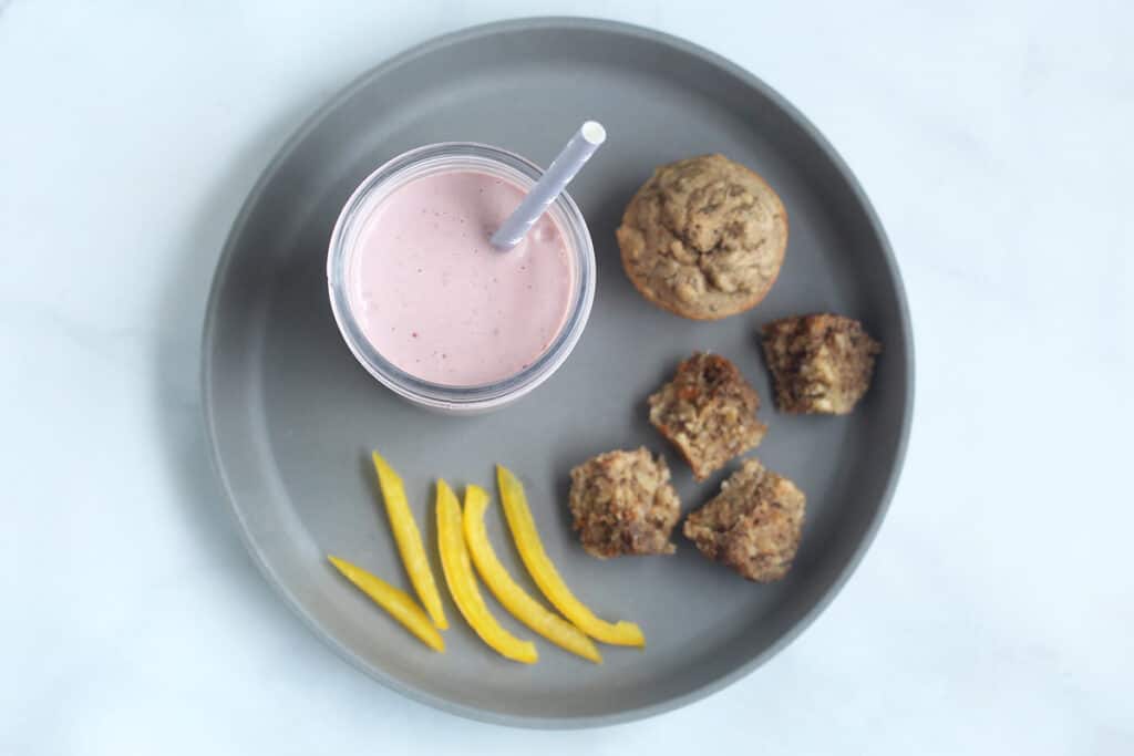 smoothie with muffins on gray plate.