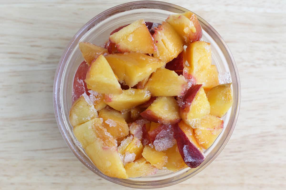 Peaches cut up in glass bowl for peach muffins. 