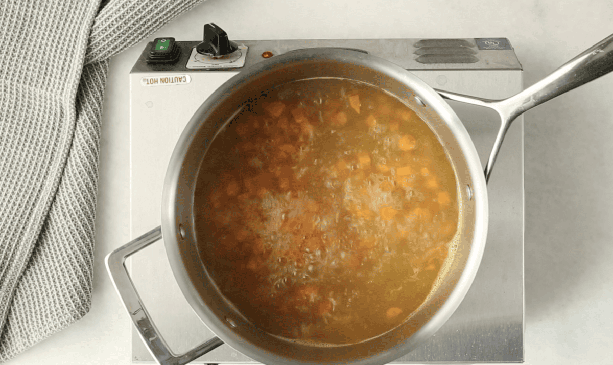 Broth with veggies in pot for alphabet soup.