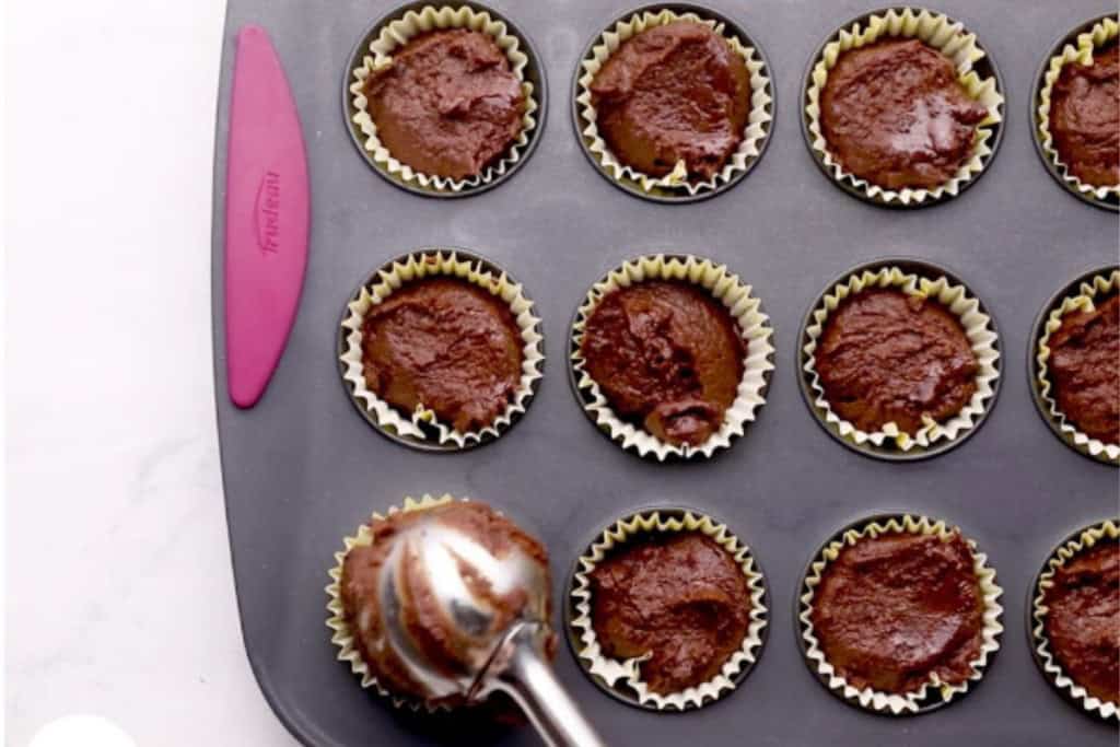 Black bean brownie batter being added to mini muffin cups.