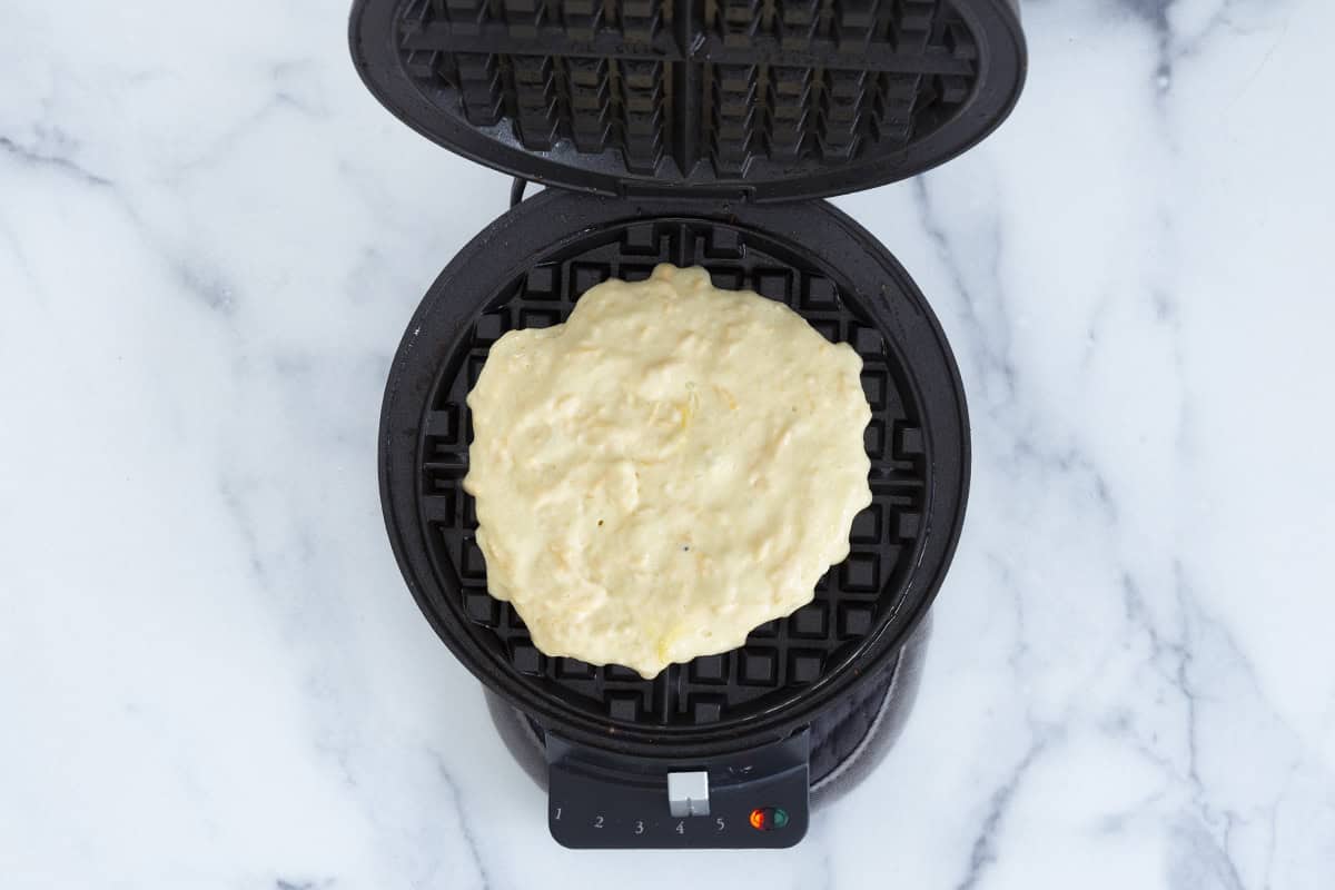 Cheese waffle in waffle iron before cooking. 