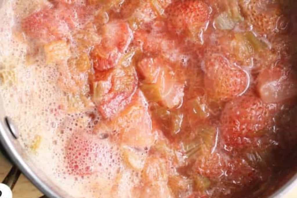 Strawberries and rhubarb cooking in pot for jam.