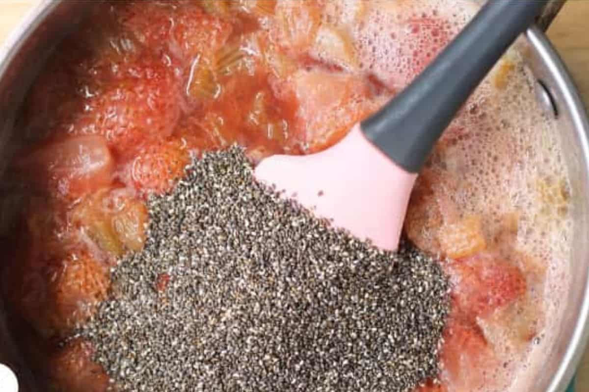 Spatula stirring in chia seeds into cooked strawberry rhubarb for jam.