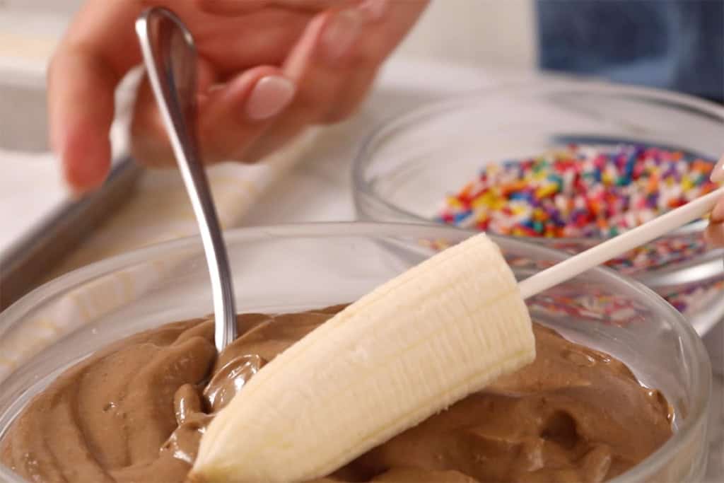 Dipping a banana in chocolate.