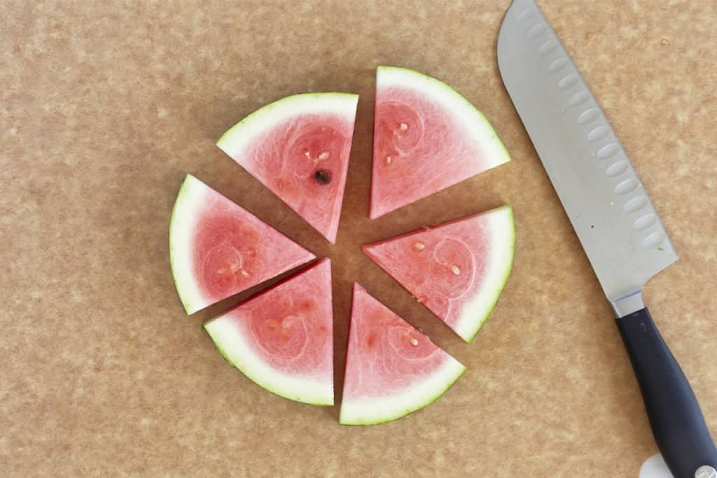 Watermelon cut into triangles on cutting board.
