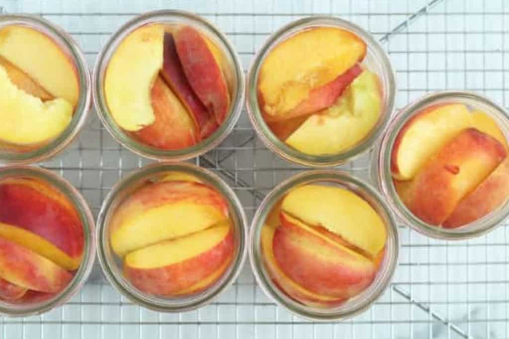 Canned peaches in glass jars without lids.