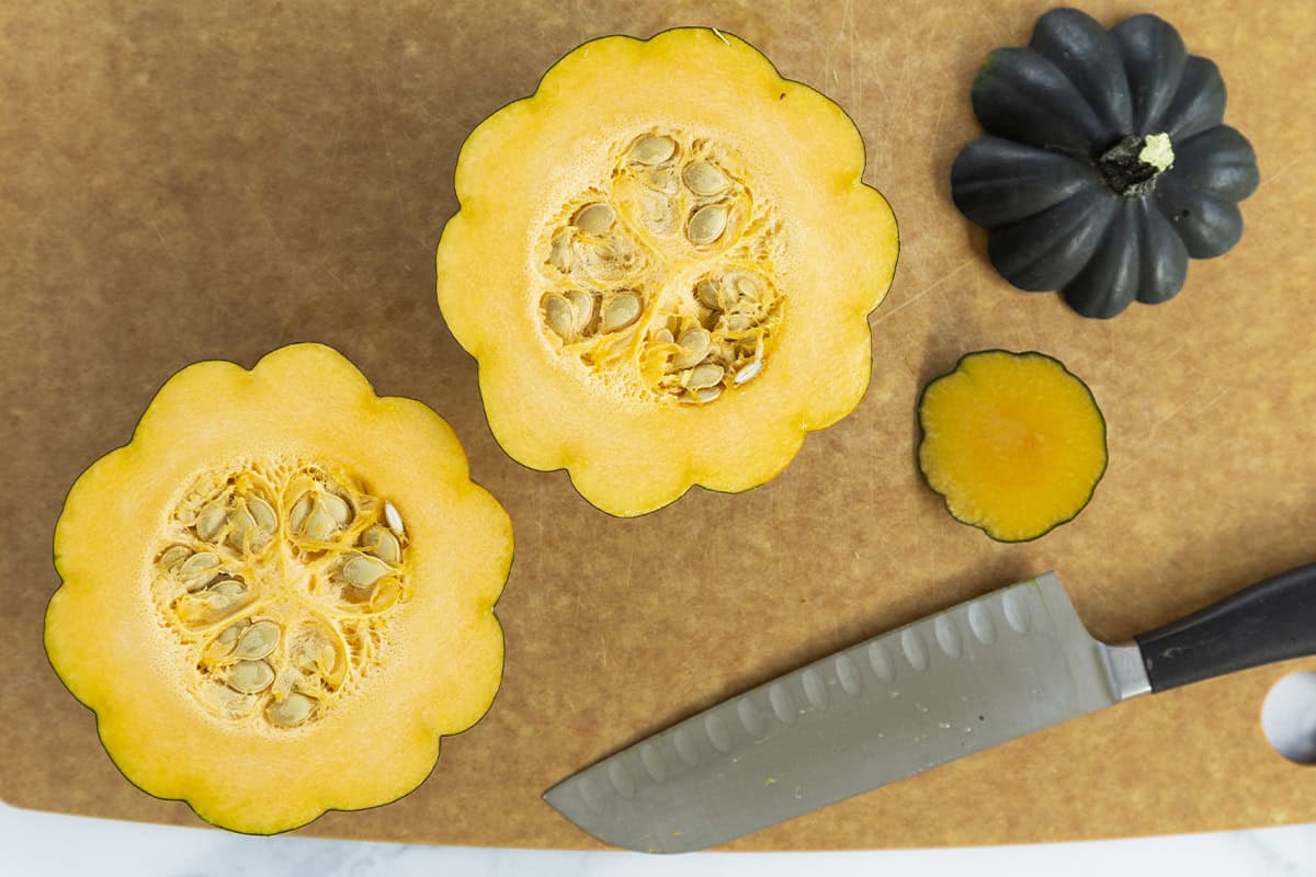 Acorn squash cut in half on cutting board. 