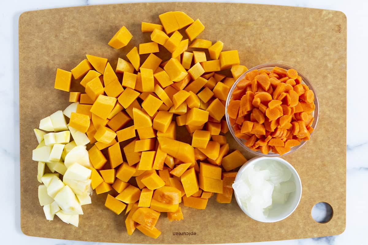 Veggies being cut on cutting board for butternut squash soup. 