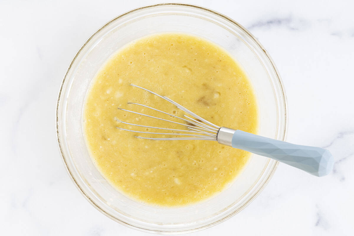 Wet ingredients for healthy brownies in glass bowl with whisk. 