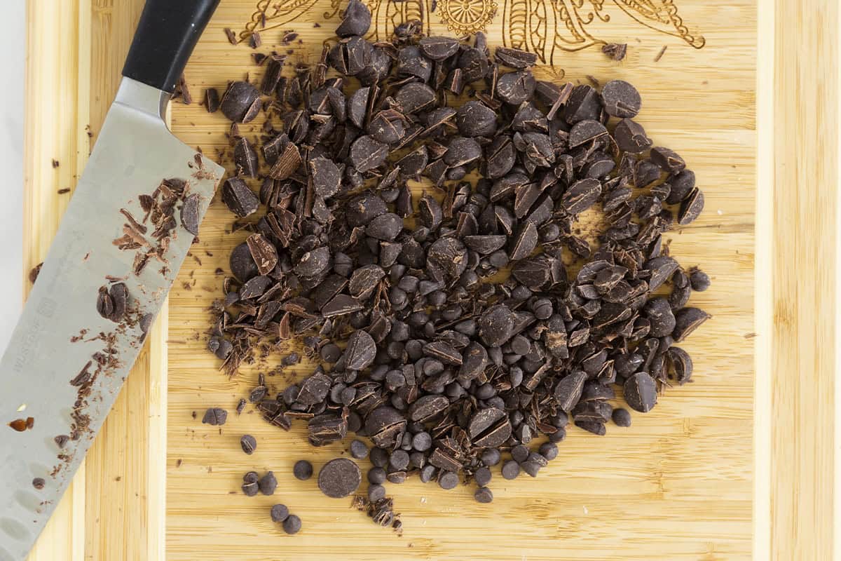 Chopping chocolate on cutting board for healthy brownies.