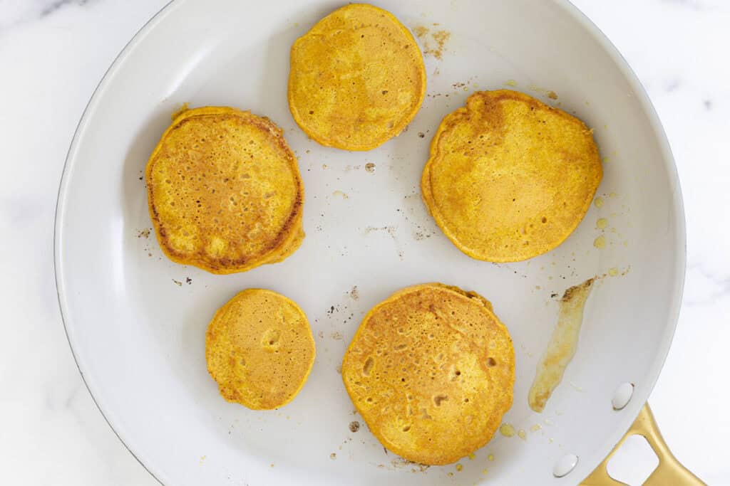 cooked pumpkin pancakes in pan on stove.