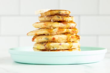 Stack of funfetti pancakes on blue plate with syrup.