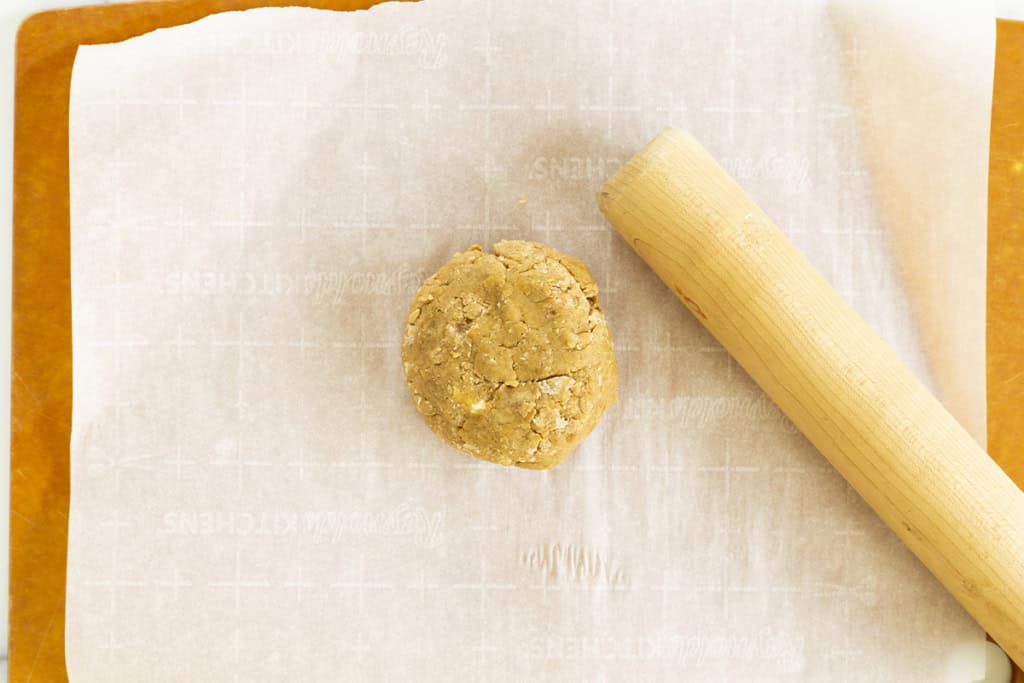 Dough for thanksgiving cookies on parchment paper with rolling pin.