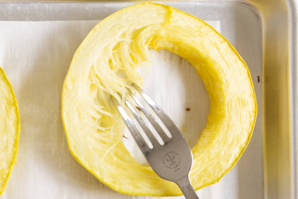 Shredding coooked spaghetti squash with a fork.