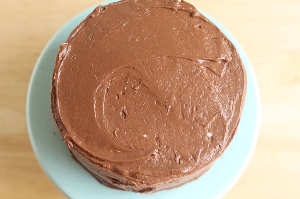 healthy chocolate cake on teal cake stand with frosting.