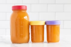 Vegetable broth in three glass jars with lids.