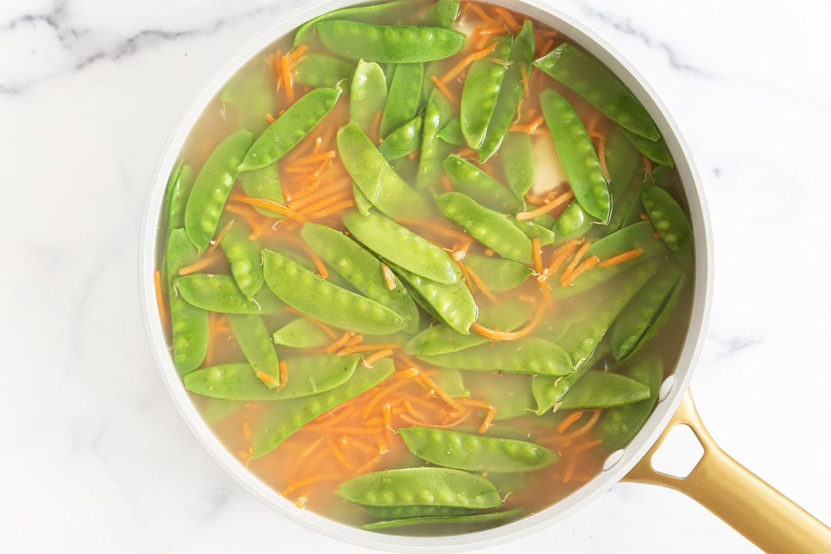 Veggies in broth for rice noodle soup.