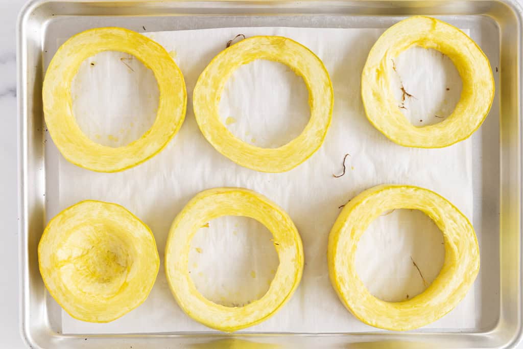 Rings of spaghetti squash on baking pan after cooking.