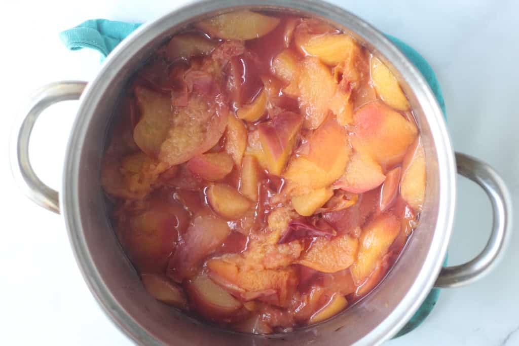 Peaches in boiling pot of water for peach sauce.
