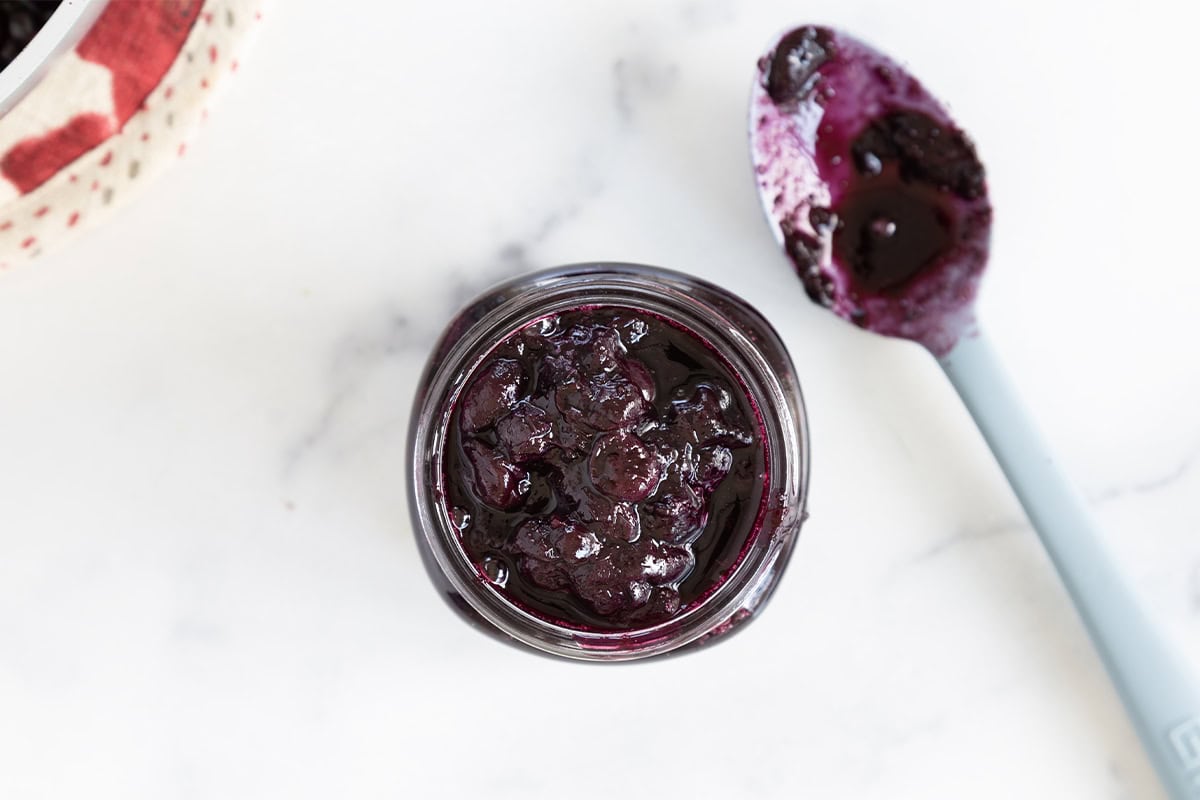Blueberry sauce in mason jar with spoon.