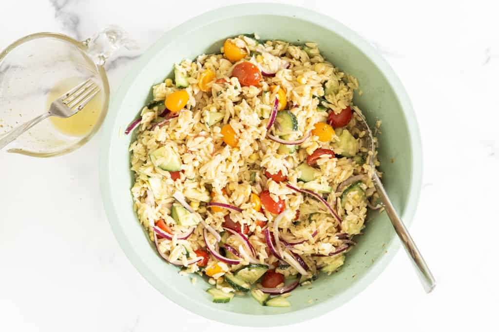 Orzo pasta salad in green bowl with spoon.