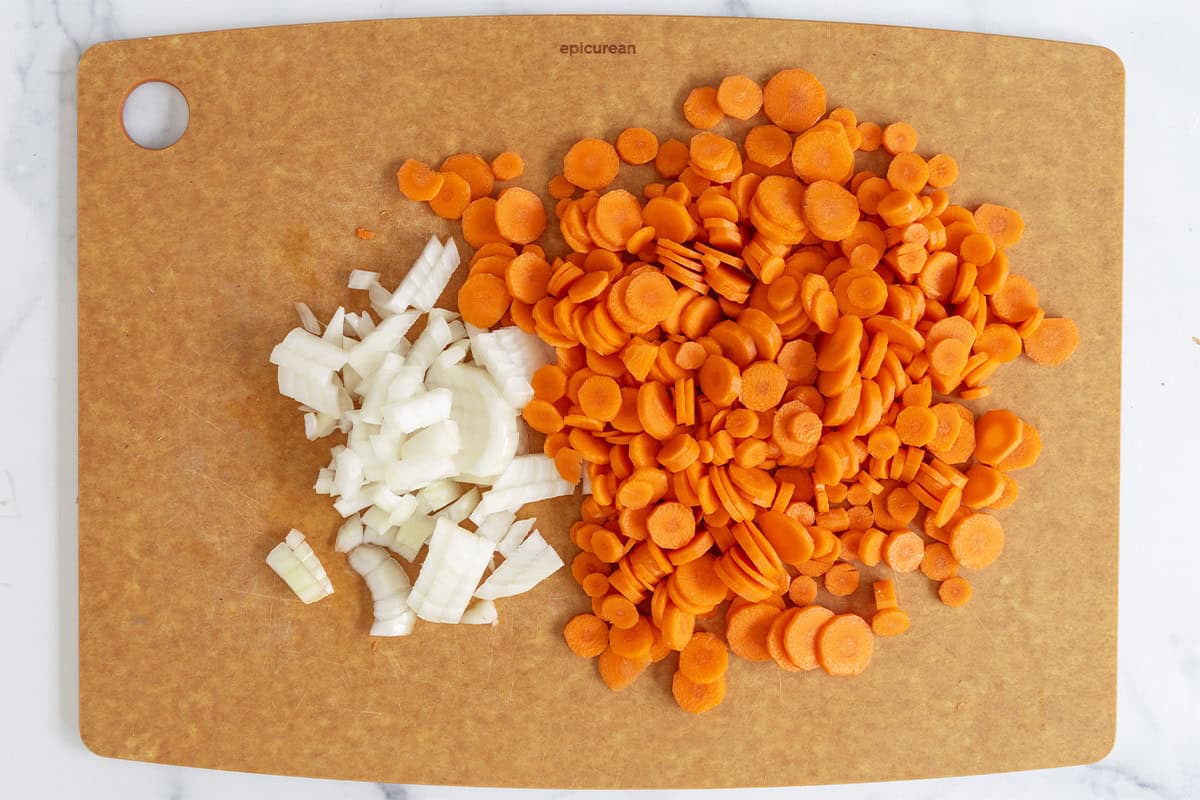 Carrots and onions on cutting board for carrot soup. 