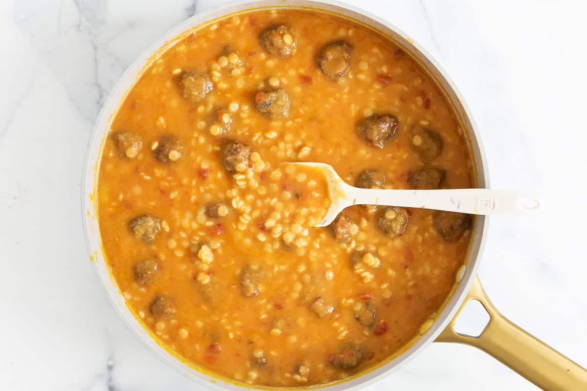 Meatball soup in pan with spoon.