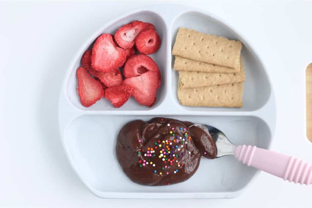 Chocolate avocado pudding with sprinkles on plate with sides.