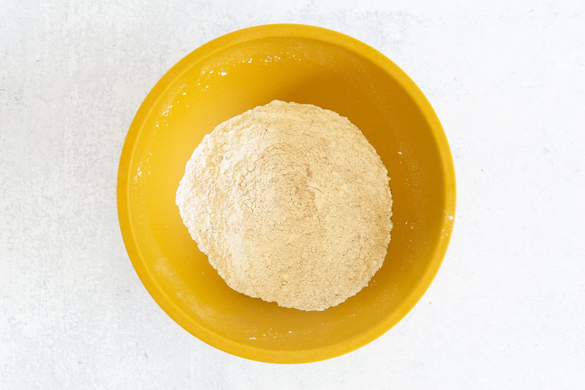 Dry ingredients in yellow bowl for apple cinnamon pancakes. 