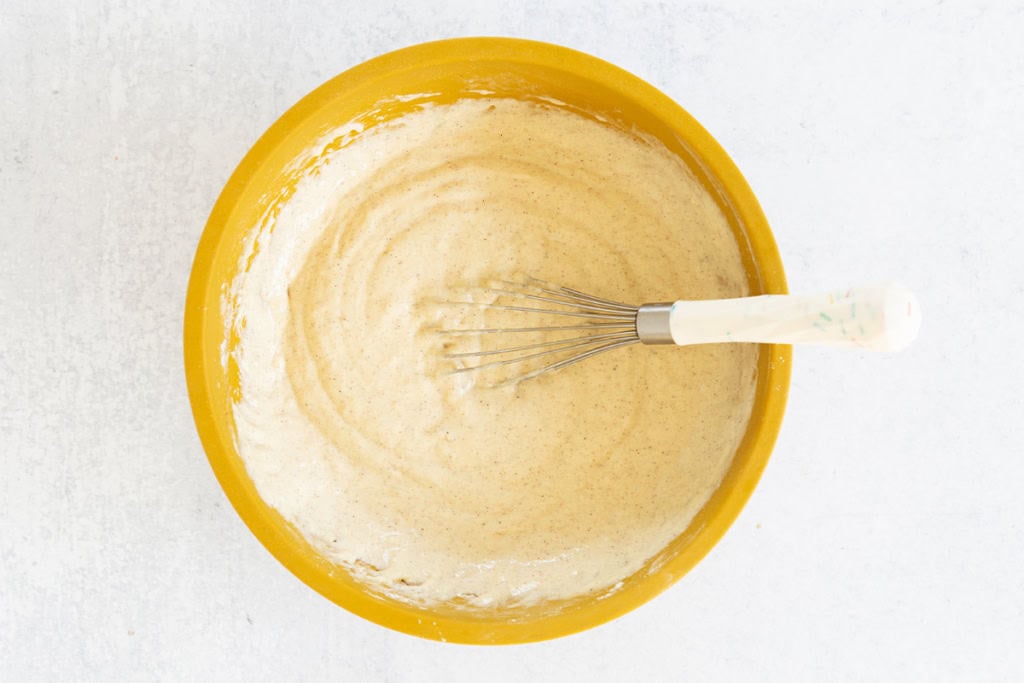 Wet ingredients in yellow bowl for apple cinnamon pancakes.