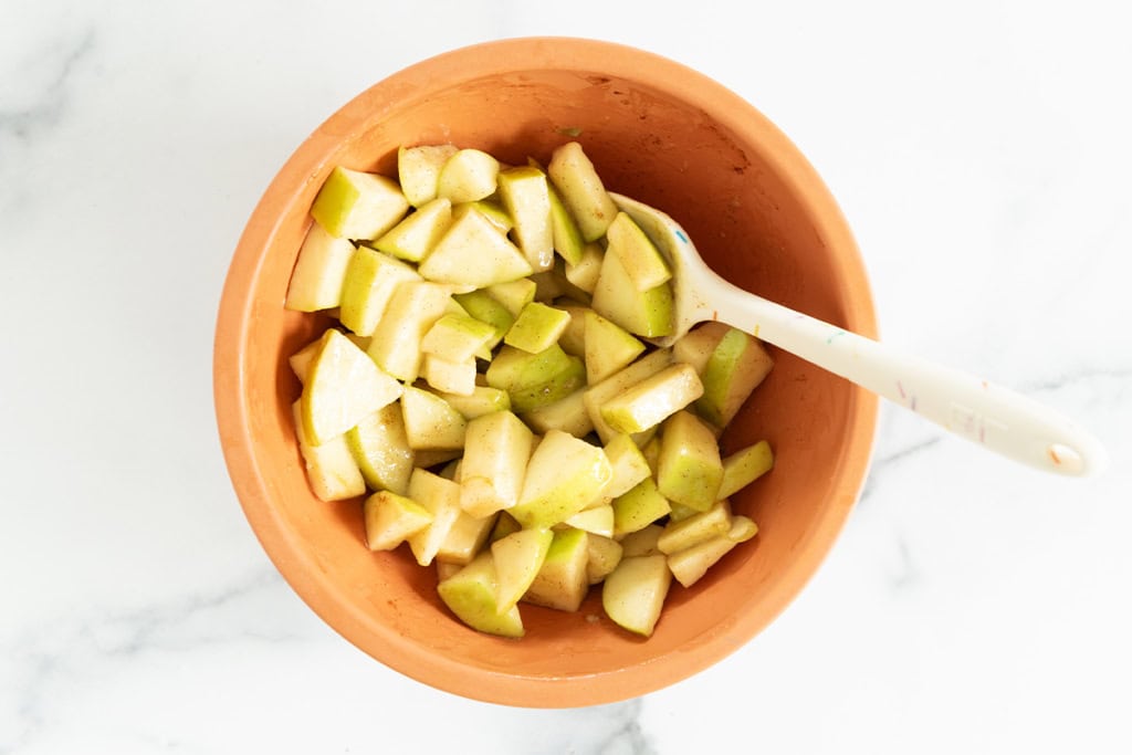 Apple pieces in bowl with spoon for air fryer apples.