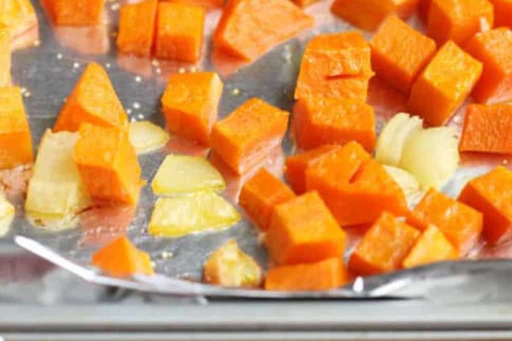 Cubes of butternut squash baking on baking sheet.