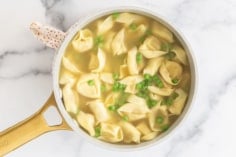 Tortellini in broth in pan.