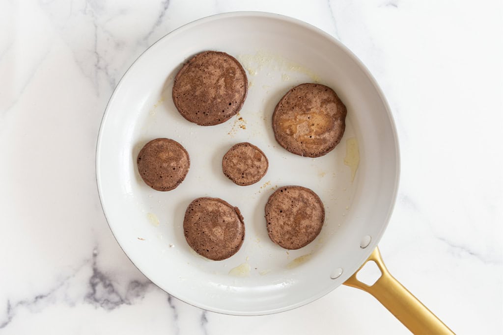 Chocolate pancakes in pan after flipping.