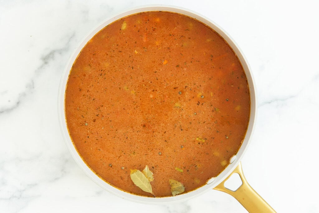 Broth in pot with veggies for lentil soup.