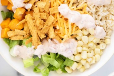 Burrito bowls on two plates with toppings and sides.