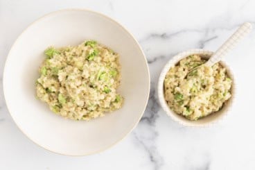 Cheesy broccoli rice in two white bowls.