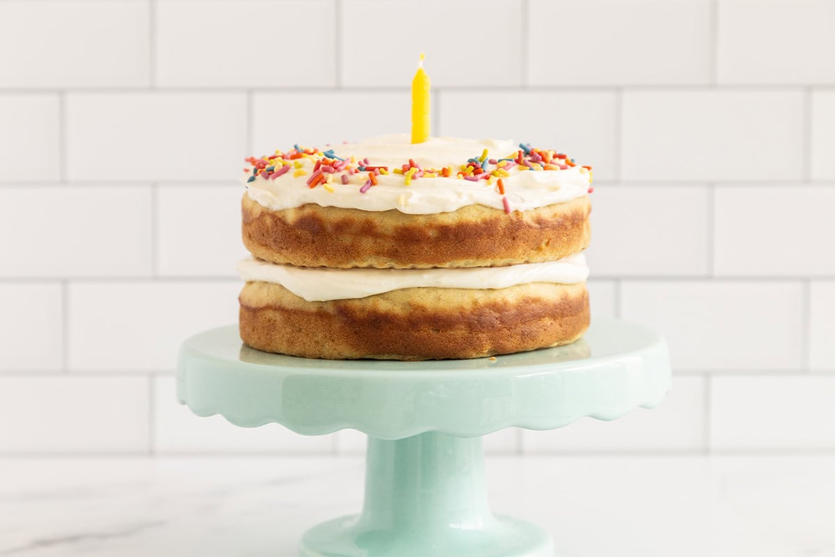 First birthday cake on cake stand with candle. 