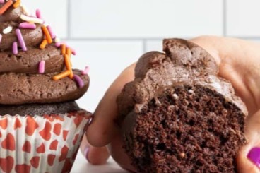 Chocolate cupcakes with hand holding one.