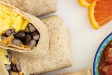 Breakfast burritos on white plate with sides.